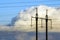 Electricity transmission power lines against white clouds. High