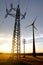 Electricity transmission pylon and wind turbine at sunset.