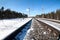 Electrified railway line among wintry forest at sunny day, close-up view at rail-track
