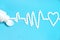 An electrocardiogram made of white tablets with a heart symbol. Blue background. A white pill jar. The concept of cardiac