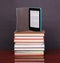 Electronic book reader and pile old books on wood desk