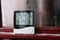 Electronic clock, calendar, thermometer, and hygrometer, against the background of condensation on glass, high humidity. Digital