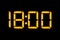 Electronic digital clock with orange numbers on a black background shows the time. Eighteen zero zero in the evening. Isolate,