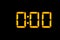 Electronic digital clock with orange numbers on a black background shows the time Twelve zero zero or twenty four in the morning.