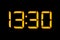 Electronic digital clock with yellow numbers on a black background shows the time Thirteen thirty hours of the day. Isolate, close