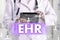 Electronic health record. EHR on the touch screen with medicine icons on the background blur Doctor