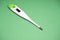 Electronic medical thermometer on a green background