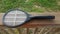 Electronic metal tennis racket insect killer on wood railing