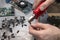 An electronic service worker cuts the tip of the capacitor with a pliers.