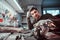 Electronic technician in goggles, leaning on a desk in a repair shop, looking at a camera with a thoughtful look