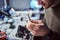 Electronic technician mending a broken phone, looking closely at the little bolt holding it with tweezers