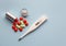 Electronic thermometer and colored pills on a blue background