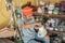 Electronics repairman holding a broken blender against the backdrop of a shelf of damaged goods