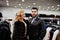 Elegance blonde girl in fur coat and stylish turkish man at the store of fur coats and leather jackets