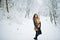 Elegance curly girl in fur coat at snowy forest park at winter