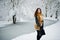 Elegance curly girl in fur coat at snowy forest park at winter.