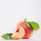 Elegance ripe peach with green young leaves and juicy piece on white soft wood background, copy space, closeup, square.
