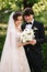 Elegand bride in beautiful white wedding dress with handsome groom in the park. Green background