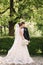 Elegand bride in beautiful white wedding dress with handsome groom in the park. Green background