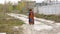 Elegant adult woman walks along a path in the waste-ground.