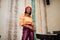 Elegant afro american woman in red french beret, big gold neck chain polka dot blouse and leather pants pose indoor