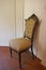 Elegant antique upholstered chair with carvings, in front of white wall.