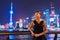 Elegant Asian woman smiling enjoying night club going out in black fashion dress by the Bund river in Shanghai view of city lights