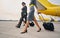 Elegant aviator and two stylish stewardesses with luggage moving ahead