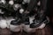 Elegant black leather winter boots on female legs near a beautiful festive Christmas tree with white vintage toys. New Year`s sal