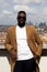 Elegant black man posing leaning on the railing of a roof terrace with the Madrid skyline in the background