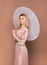 Elegant blond woman in pink haute couture with parasol