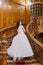 Elegant brunette bride at old vintage palace walking up big wooden stairs