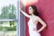 elegant brunette woman in white dress stands near big window of modern building (skyscraper,tower)