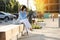 Elegant businesswoman holds paper cup with coffee or tea to go, messaging on smartphone and relaxing free time outside