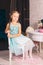 elegant caucasian girl sits on a chair near the dressing table and looking in the camera