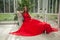 Elegant celebrity woman in red silky dress sitting on vintage armchair