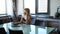 Elegant and cheerful woman. Cheerful young beautiful woman looking at laptop with smile while sitting at table in her