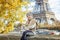 Elegant child sitting on parapet on embankment near Eiffel tower