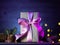 Elegant Christmas gift box with purple ribbon. Backlight background, bokeh garlands. Christmas sale