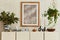 Elegant composition of stylish living room interior with mock up poster frame, beige sideboard, plants and vintage personal.