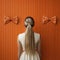 Elegant Conceptual Photography Of A Girl With A Ponytail And Bows On An Orange Wall