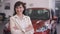 Elegant confident beautiful woman crossing hands smiling looking at camera standing in car dealership indoors. Portrait