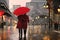Elegant couple with red umbrella and coat on rainy evening
