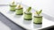 An elegant culinary creation of cucumber sushi artfully arranged on a white plate.