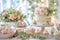 Elegant dessert table with a two-tiered wedding cake, cupcakes, and floral arrangements