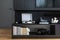 Elegant details of living room interior. Vinyl recorder, books and small personal accessories on black commode. Modern home decor.