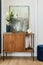 Elegant details of modern glamour interior design with wooden sideboard, painting and stylish personal accessories. Template.