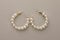 Elegant earrings with pearls on beige background, top view
