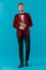 Elegant fashion model wearing red velvet tuxedo on blue background