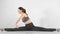 Elegant female ballet dancer during warming up sits at split enjoy elastic shape